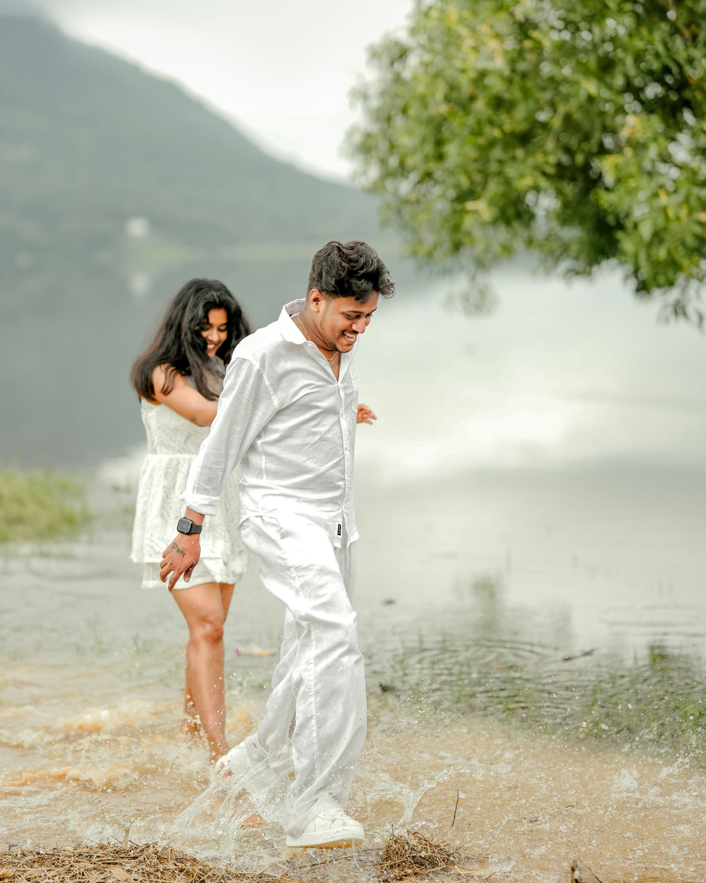 A couple sharing a playful moment beside a mountain lake